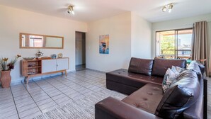 Una sala de estar moderna con un conjunto de sofá, un mueble de madera y un amplio ventanal con cortinas.