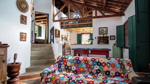A cozy living room with a colorful quilted sofa, wooden beams, a staircase, and a billiards table. - Casa de campo c lazer, bem equipada, pet friendly (Santana de Parnaíba)