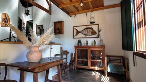 A rustic interior with a wooden table, a cabinet with glass doors, and a hanging fish decoration. - Casa de campo c lazer, bem equipada, pet friendly (Santana de Parnaíba)