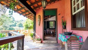 An outdoor patio area with wooden furniture, a table with a colorful tablecloth, and a potted plant. - Casa de campo c lazer, bem equipada, pet friendly (Santana de Parnaíba)