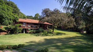 A house with a red roof, surrounded by a well-maintained lawn and various plants. - Casa de campo c lazer, bem equipada, pet friendly (Santana de Parnaíba)