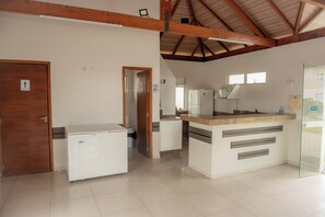 A spacious kitchen with a central island, a refrigerator, and a glass door leading outside. - Apto com churrasqueira, Wi-Fi e ótima localização (Curitiba)