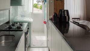 Een kleine keuken met een gasfornuis, een koffiezetapparaat en een eethoek met een tafel en stoelen.