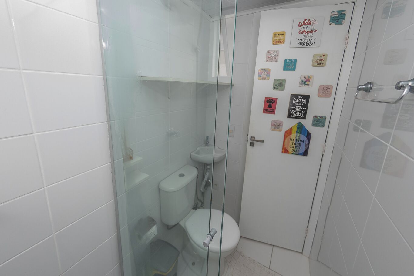 A small, tiled bathroom with a glass shower enclosure, a toilet, and a sink.