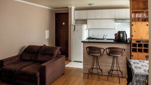 Een woonkamer met een bruine bank en twee rieten barstoelen.