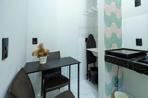 Cozinha compacta com bancada preta, uma pequena mesa de jantar com duas cadeiras e um varal fixado na parede.