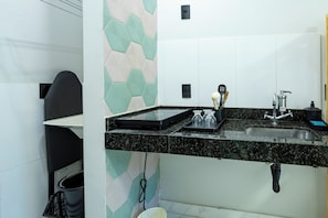 Uma cozinha moderna com bancada de granito preto, pia de aço inoxidável e backsplash com padrão geométrico.