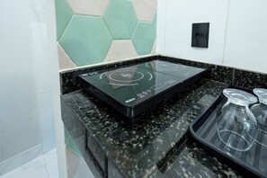 Uma cozinha com fogão por indução preto, bancada de granito e painel de azulejos hexagonais.