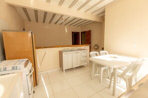 A kitchen with a refrigerator, a wooden countertop, cabinets, and a dining area with a table and chairs. - Apto c/ Wi-fi,  garagem e vista das montanhas (Angra dos Reis)