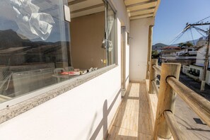A balcony with a wooden railing, a window with a view of the street, and a tiled floor. - Apto c/ Wi-fi,  garagem e vista das montanhas (Angra dos Reis)