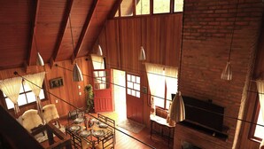 A cozy, rustic interior with wooden beams, a fireplace, and a dining area with a table set for four.