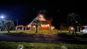 A two-story house with a sloped roof, large windows, and a well-lit front entrance.
