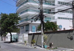 A modern building with balconies, a gated entrance, and potted plants. - Ótimo Apto à 650m da praia do Forte em Cabo Frio (Cabo Frio)