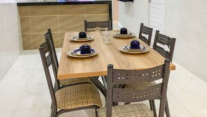 Un'area pranzo con tavolo in legno apparecchiato per sei persone, circondato da sedie in vimini.