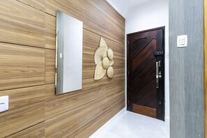 Ein Flur mit einer Holzwand, einer weißen Tür mit Strukturmuster und einem an der Wand befestigten Lichtschalter.