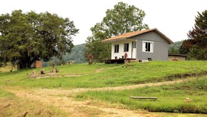 Una casa d'un pis amb teulada inclinada, un porxo amb una banca i una petita zona de jardí amb farquetes.