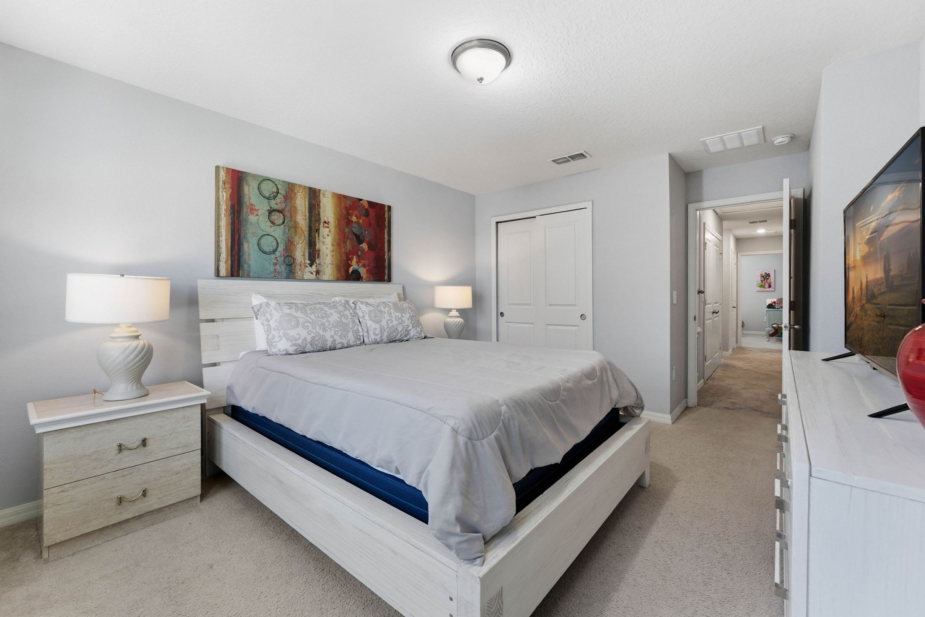 Une chambre à coucher avec un lit, des tables de chevet, une commode et un tableau au mur.