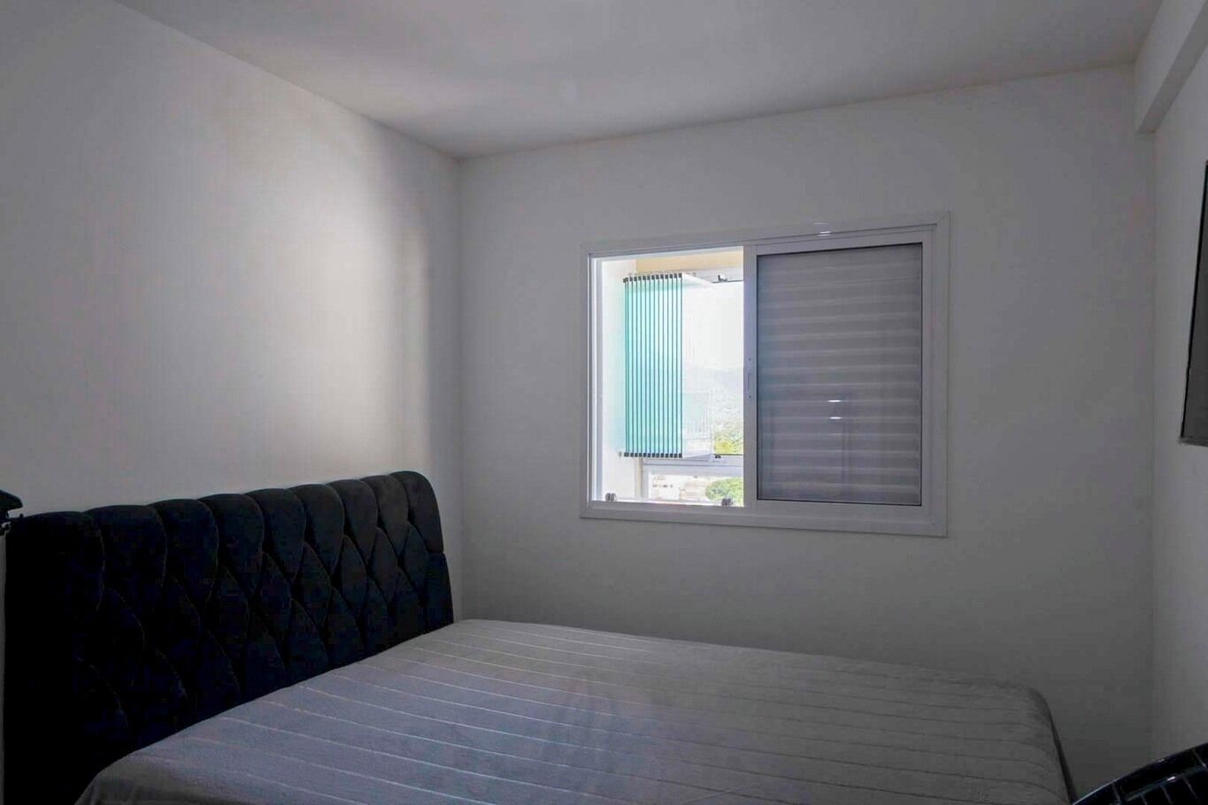 Ein kleines Zimmer mit einem Einzelbett, Fenster und Kopfteil.