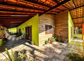 A covered patio with a hammock, potted plants, and a view of a green lawn.