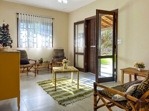 A spacious living area with a large window, a wooden door leading outside, and a Christmas tree.