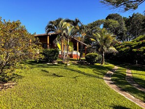 A house with a well-maintained lawn, a pathway, and a variety of tropical plants.