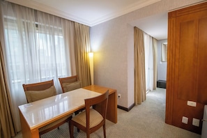 Ein Hotelzimmer mit einem Holztisch, zwei Stühlen, Teppichboden und einer Tür.