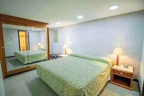 Ein Hotelzimmer mit Bett, Nachttisch, Spiegel und Lampe.