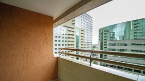 A balcony with a metal railing, a view of high-rise buildings, and a plain wall. - Apto no Brasil 21 - Conforto e Localização Central (Brasilia)