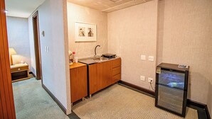 A compact hotel bathroom with a sink, wooden cabinet, and a small refrigerator. - Apto no Brasil 21 - Conforto e Localização Central (Brasilia)