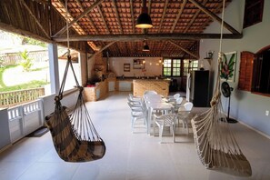A spacious kitchen with a brick island, white chairs, and a hanging hammock.