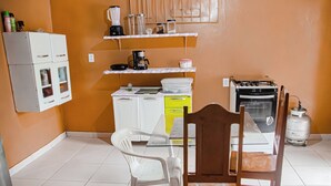 A compact kitchen with white cabinets, a yellow countertop, a coffee maker, a blender, and a gas stove. - Casa bem equipada com WiFi e ótima localização (Belém)