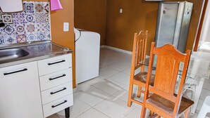 A kitchen with a white refrigerator, a microwave, and a wooden dining table with chairs. - Casa bem equipada com WiFi e ótima localização (Belém)