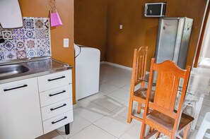 Eine Küche mit einem weißen Kühlschrank, einer Mikrowelle und einem Holzespeisetisch mit Stühlen.