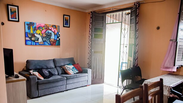 A living room with a grey sofa, a television, and a painting on the wall. - Casa bem equipada com WiFi e ótima localização (Belém)