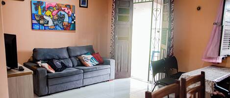A living room with a grey sofa, a television, and a painting on the wall.