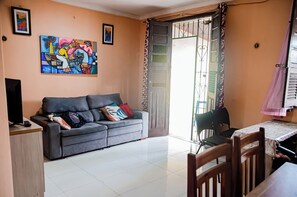 Ein Wohnzimmer mit grauem Sofa, einem Fernseher und einem Bild an der Wand.