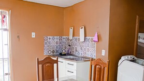A compact kitchen with a dining area, featuring a tiled backsplash, a washing machine, and a small dining table with chairs. - Casa bem equipada com WiFi e ótima localização (Belém)