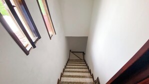 Una stretta scala con gradini in legno e una ringhiera, che conduce a un piano superiore.