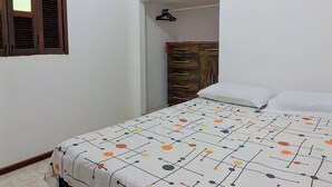 Una camera da letto con un letto, un armadio in legno e una finestra con persiane.