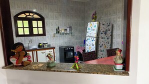 Una cucina con un piano di lavoro in marmo, un frigorifero decorato con disegni per bambini e una finestra con cornice decorativa.