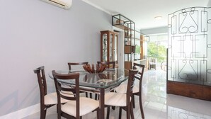 Un área de comedor con una mesa de vidrio y sillas de madera, una estantería y un separador decorativo de vidrio.