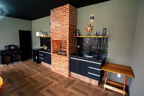 A modern kitchen with a brick oven, black cabinetry, and a wooden floor. - Casa pet friendly c piscina, churrasqueira e wi-fi (Saquarema)