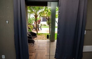 A doorway leading to an outdoor patio area with a seating arrangement and a palm tree. - Casa pet friendly c piscina, churrasqueira e wi-fi (Saquarema)