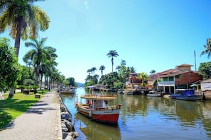 Ein Kanal mit Booten, ein gepflasterter Weg und Gebäude mit roten Dächern.