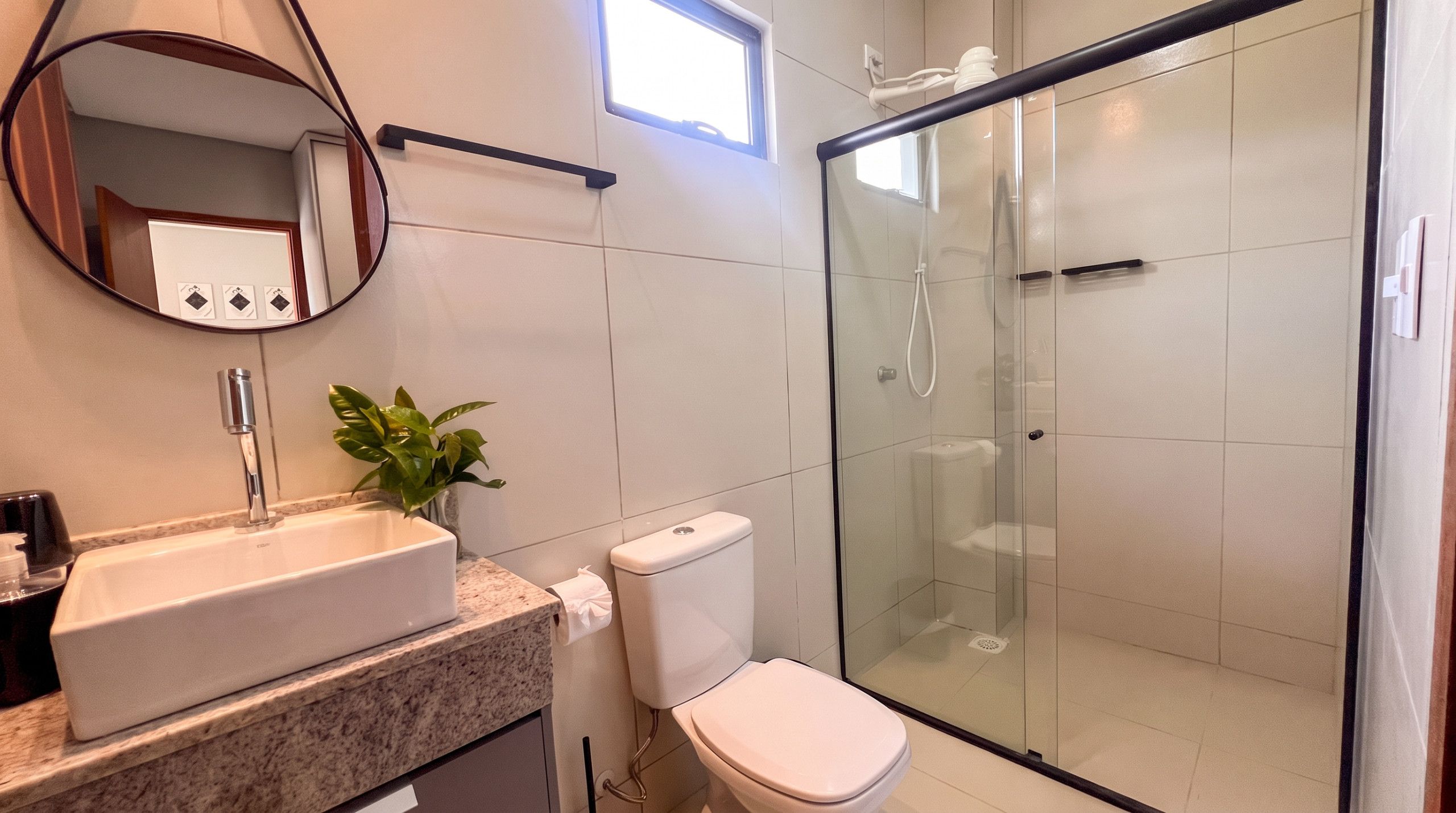 A modern bathroom with a glass shower enclosure, a sink with a marble countertop, and a toilet.