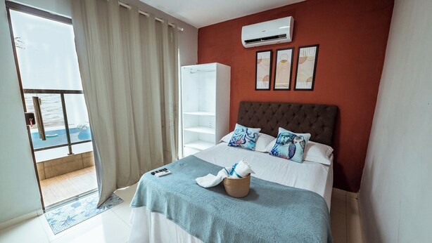 A hotel room with a bed, a wardrobe, a balcony with a view, and an air conditioning unit. - Casa em Jacumã, com piscina, 5 suites e Fliperama (Conde)