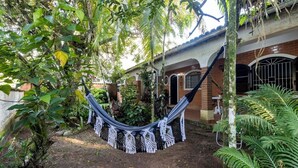 Una hamaca en un jardín exuberante, con un edificio de ladrillo al fondo.
