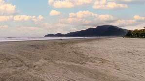 Una playa con una montaña al fondo, una bicicleta y algunas personas.