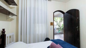 Un dormitorio con cama, una mesita de noche, una ventana con cortinas y vistas al exterior.