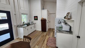 Una cocina con armarios blancos, una mesa de comedor de madera y un refrigerador.